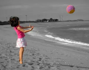 Criança jogando bola na praia