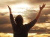 Man holding arms up in praise against golden sunset